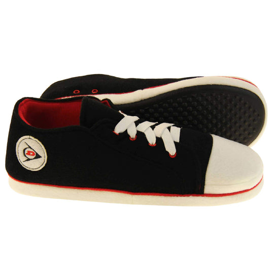 Mens sneaker slippers. Black soft fabric upper in low-rise sneaker style. With white elasticated laces and white circle with Dunlop logo to the side. White edge around the sole of the shoe. Red textile lining. Black sole with bumps for grips. Both feet from side profile with left foot on its side to show the sole.