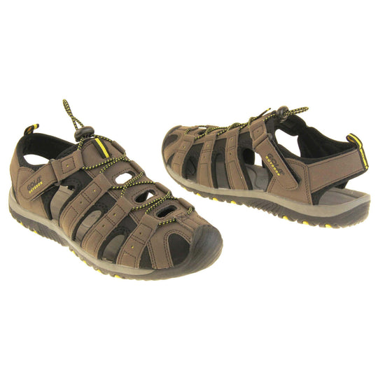 Mens sport sandals. Traditional style sandal with brown and black fabric strappy upper. Black rubber toe caps and black synthetic sole with yellow grips to the bottom. Elasticated laces to the front of the shoe and touch fasten strap by the ankle. Both feet about an inch apart at an angle facing top to tail.