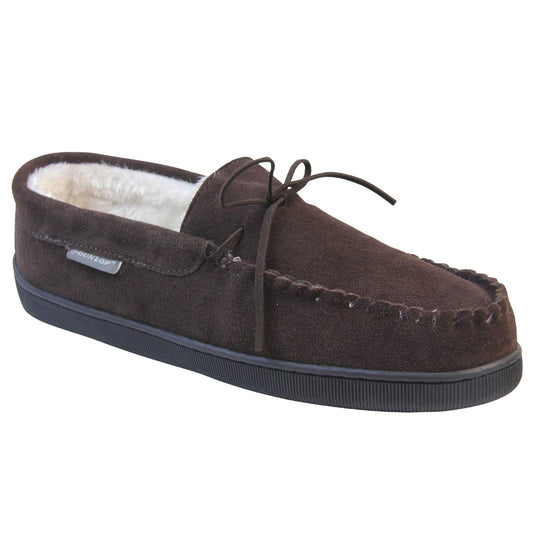 Mens suede moccasin slippers. Closed back slippers in a moccasin style with dark brown suede leather upper and bow. Cream faux fur lining. Thick black sole. Right foot at an angle.