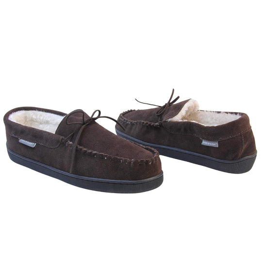 Mens suede moccasin slippers. Closed back slippers in a moccasin style with dark brown suede leather upper and bow. Cream faux fur lining. Thick black sole. Both shoes at an angle spaced about an inch apart, facing top to tail at an angle.