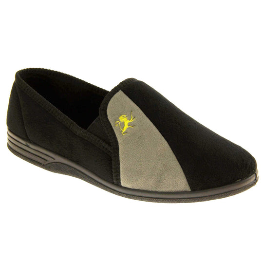 Mens Velour Slippers. Full back slippers for men with a black velour uppers with grey stripe with a yellow embroidered lion on. Black elasticated panels joining the tongue to the top of the slippers. Black textile lining. Right foot at an angle.