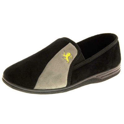 Mens Velour Slippers. Full back slippers for men with a black velour uppers with grey stripe with a yellow embroidered lion on. Black elasticated panels joining the tongue to the top of the slippers. Black textile lining. Left foot at an angle.