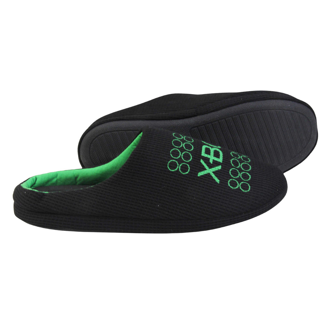 Mens xbox mule slippers. Mule style slippers with black textile uppers with green Xbox branding on the top. Green and black textile lining and firm black sole. Both feet from a side profile with the left foot on its side behind the the right foot to show the sole.