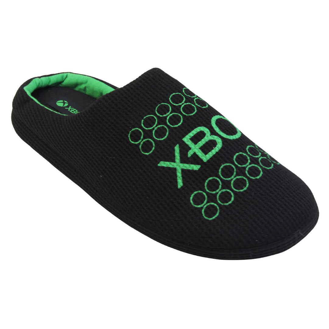 Mens xbox mule slippers. Mule style slippers with black textile uppers with green Xbox branding on the top. Green and black textile lining and firm black sole. Right foot at an angle.