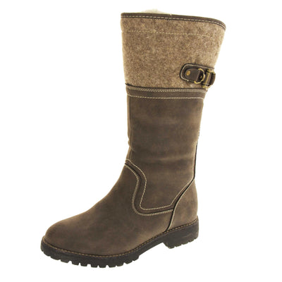 Mid calf boots. Women's boot in a below the knee style. With a brown faux leather upper and brown felt effect collar with brown buckle detail. Black sole with chunky grip to the bottom. Zip fastening to the inside leg. Cream faux fur lining. Left foot at an angle.