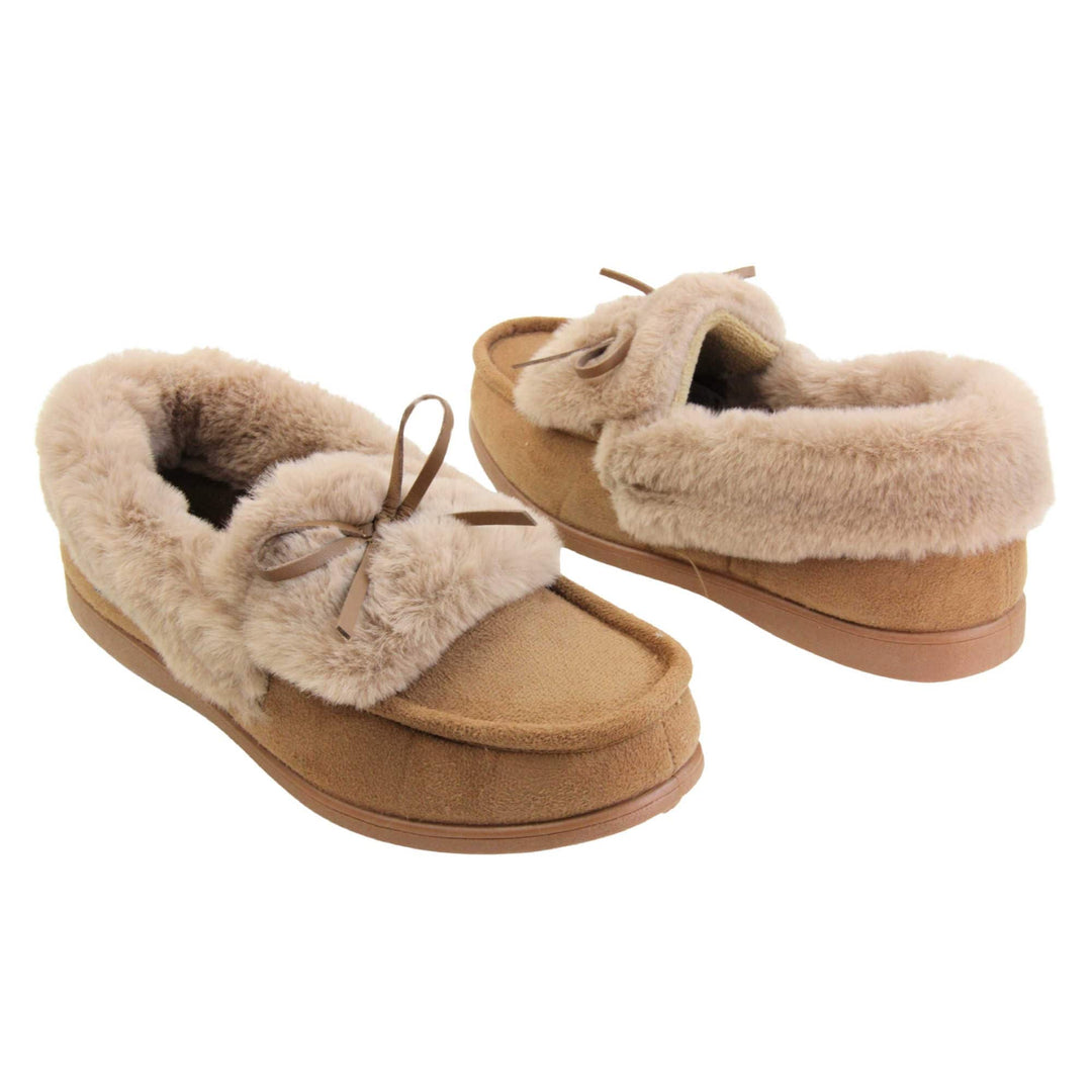 Moccasin slippers womens. Moccasin style slipper with a brown camel coloured faux suede upper and bow to the top. Light brown faux fur collar, tongue and lining. Brown rubber sole. Both feet at an angle facing top to tail.