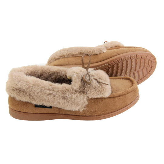 Moccasin slippers womens. Moccasin style slipper with a brown camel coloured faux suede upper and bow to the top. Light brown faux fur collar, tongue and lining. Brown rubber sole. Both feet from a side profile with the left foot on its side behind the the right foot to show the sole.