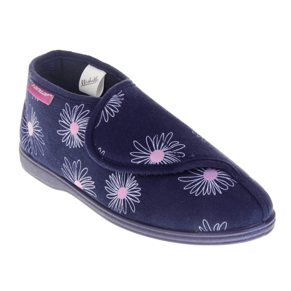 Navy blue slippers. Womens bootie style slipper with a navy blue textile upper with a white and pink flower print. Touch fasten tab to the top and blue textile lining. Firm navy sole. Right foot at an angle.