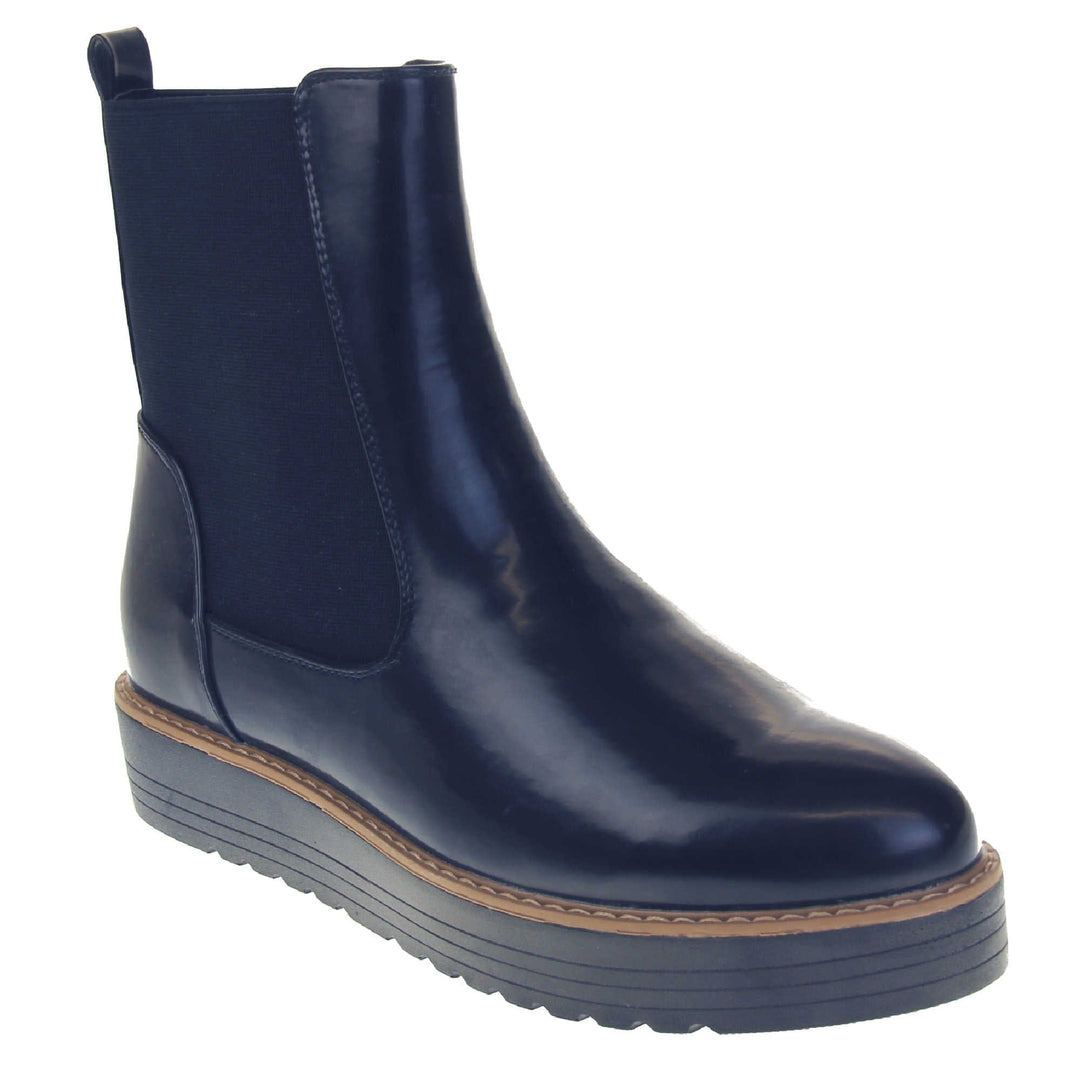 Navy flat ankle boots. Faux leather, tall Chelsea boot style with a navy blue coloured upper. Blue elasticated panels at the ankles and a navy loop at the heel to help pull them on. Black coloured low platform sole. Right foot at an angle