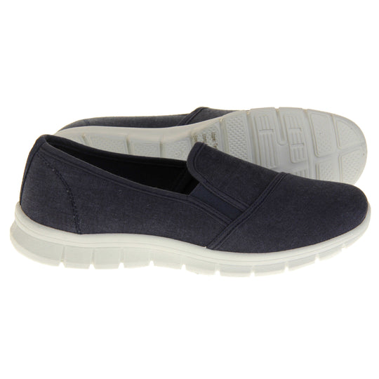 Navy slip on shoes. Women's plimsoll style shoes with a navy blue canvas upper. Navy elasticated gusset. Chunky white sole.  Both feet from a side profile with the left foot on its side behind the the right foot to show the sole.