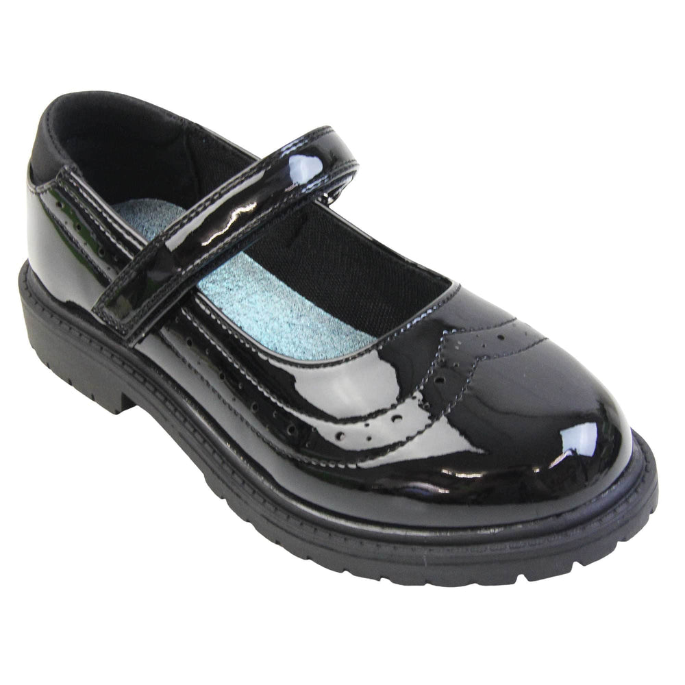 Older girls school shoes. Mary Jane style shoes with black patent faux leather uppers. With a touch fasten strap over the foot and brogue detailing around the top of the shoe. Black textile lining with a metallic blue insole. Chunky black sole with slight heel. Right foot at an angle.