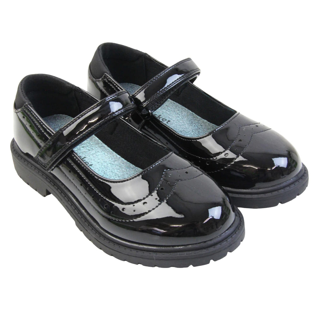 Older girls school shoes. Mary Jane style shoes with black patent faux leather uppers. With a touch fasten strap over the foot and brogue detailing around the top of the shoe. Black textile lining with a metallic blue insole. Chunky black sole with slight heel. Both feet together at an angle.