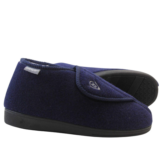 Orthopaedic slippers. Mens orthopaedic slippers in an ankle boot style. With a navy blue felt upper and white fleece lining. With an adjustable touch close top with a grey Dunlop logo on. Small grey label to the outer side edge with Dunlop written on. Thick black outdoor sole. Both feet from side profile with the left foot on its side to show the sole.