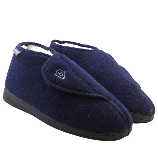 Orthopaedic slippers. Mens orthopaedic slippers in an ankle boot style. With a navy blue felt upper and white fleece lining. With an adjustable touch close top with a grey Dunlop logo on. Small grey label to the outer side edge with Dunlop written on. Thick black outdoor sole. Both feet together at an angle.