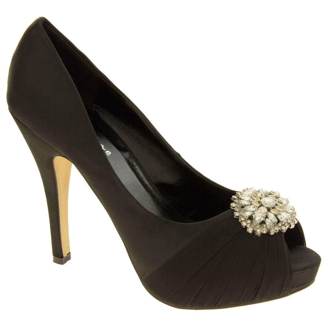 Peep toe black heels. Classic women's peep toe high heels with a black satin upper. Black insole with Sabatine branding. Black satin stiletto heel with a cream sole. Diamante cluster and ruched detailing across the toes. Right foot at an angle.
