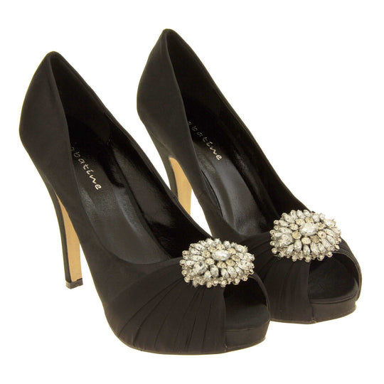 Peep toe black heels. Classic women's peep toe high heels with a black satin upper. Black insole with Sabatine branding. Black satin stiletto heel with a cream sole. Diamante cluster and ruched detailing across the toes. Both feet together at a slight angle.