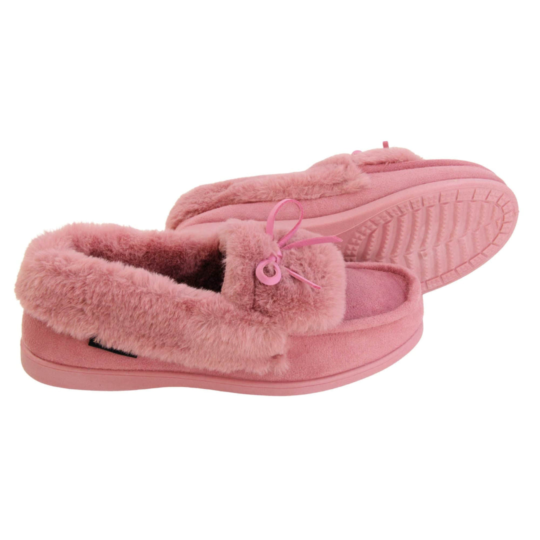 Pink moccasin slippers. Moccasin style slipper with pink faux suede upper and bow to the top. Pink faux fur collar, tongue and lining. Pink rubber sole. Both feet from a side profile with the left foot on its side behind the the right foot to show the sole.