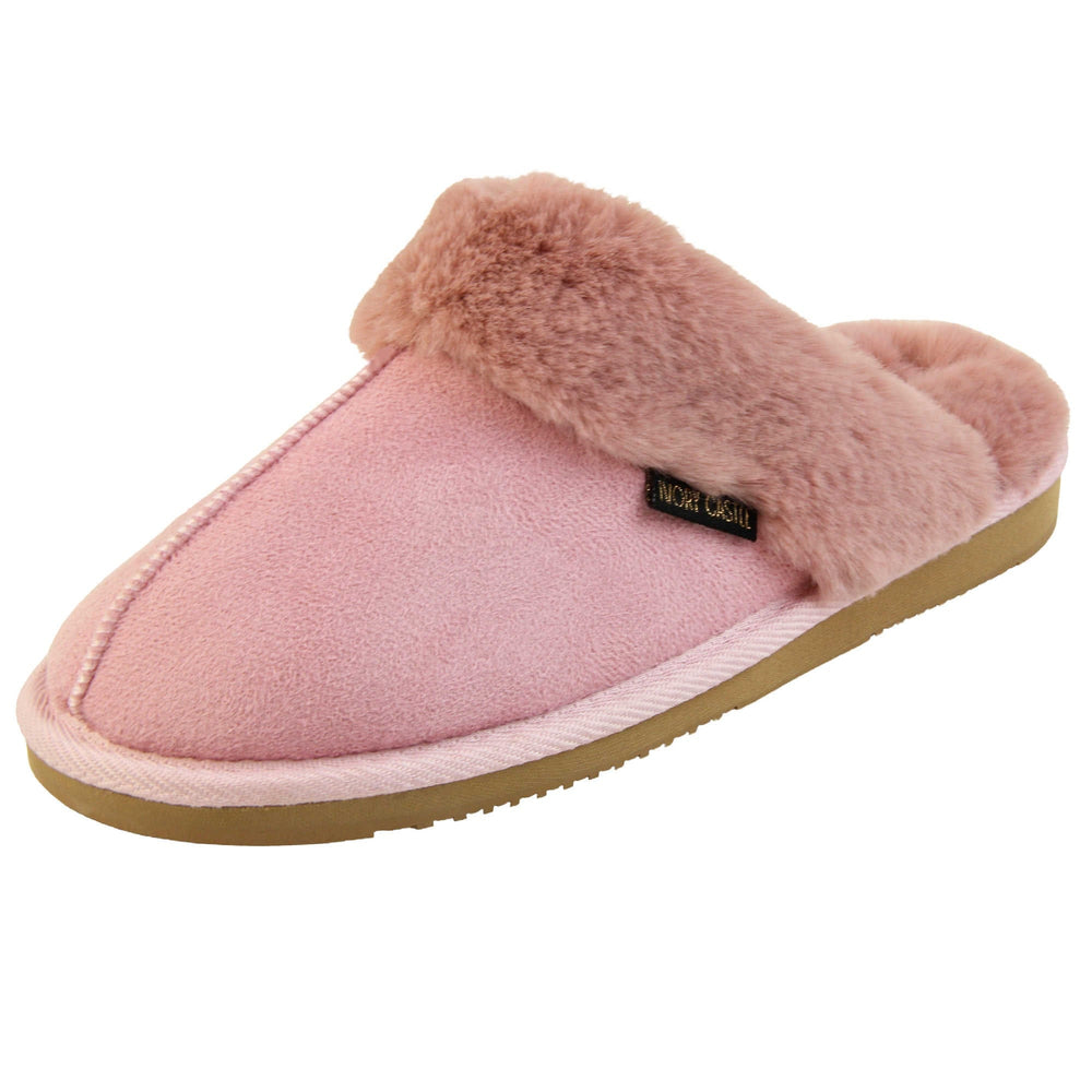 Pink Mule Slippers. Mule style slippers with pink faux suede uppers. Pink faux fur lining and collar. Firm pink outsole with grip on the bottom. Left foot at an angle.