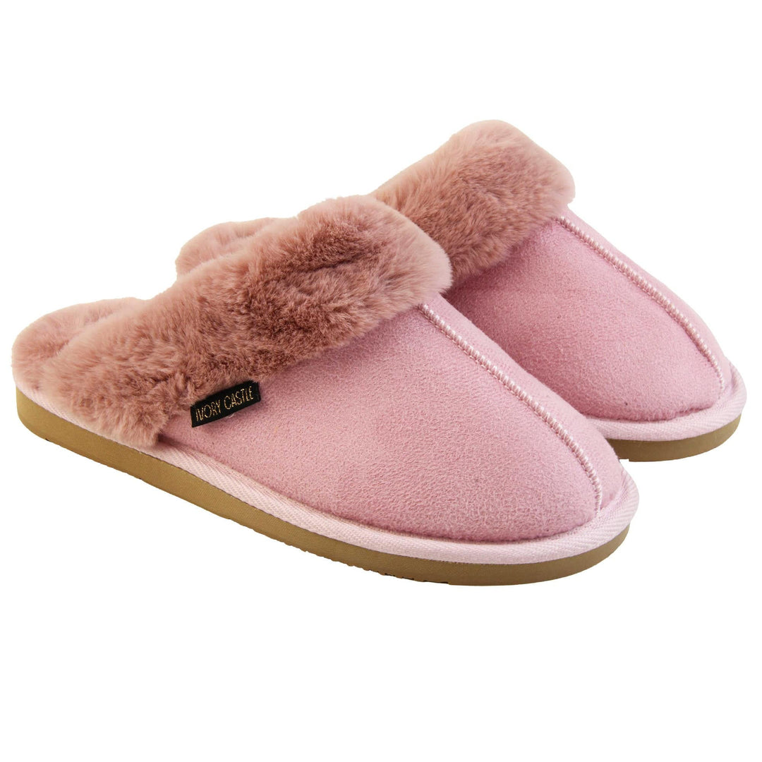 Pink Mule Slippers. Mule style slippers with pink faux suede uppers. Pink faux fur lining and collar. Firm pink outsole with grip on the bottom. Both feet together at an angle.