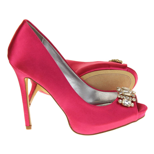 Pink satin wedding shoes. Classic women's peep toe high heels with a fuchsia satin upper. Metallic silver insole with Sabatine branding. Fuchsia satin stiletto heel with a cream sole. Diamante cluster detailing across the toes. Both feet from a side profile with the left foot on its side behind the the right foot to show the sole.