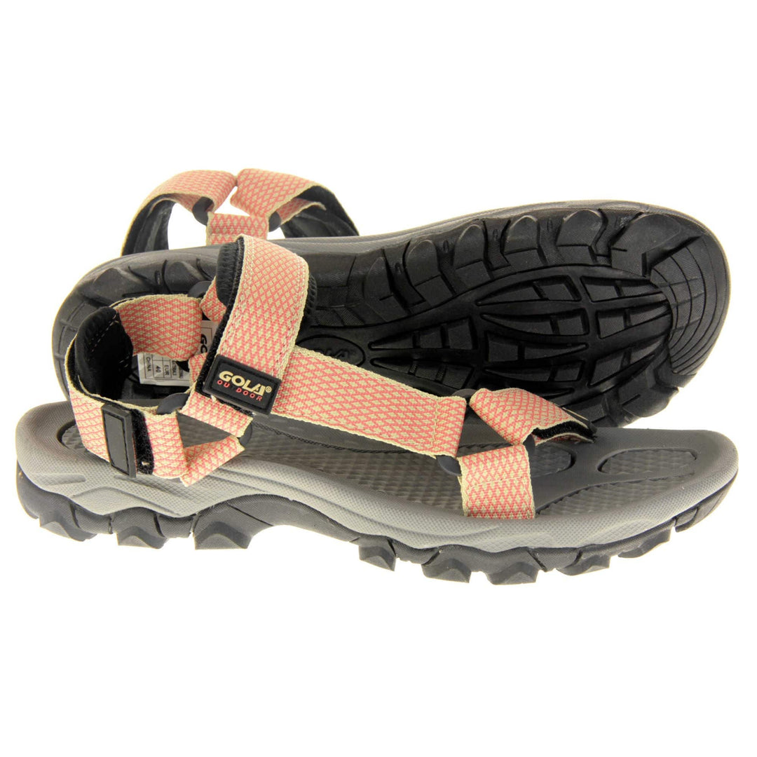 Pink walking sandals. Womens sporty style sandals. Beige textile straps with pink criss-cross pattern. Black padding to the heel and over foot strap. Touch fasten strap around the heel. Black Gola branding to the ankle of the sandal. Grey textile lining and black sole with chunky grip to the base. Both feet from a side profile with the left foot on its side behind the the right foot to show the sole.