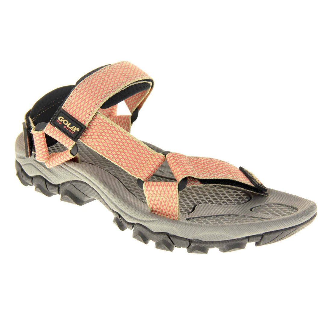 Pink walking sandals. Womens sporty style sandals. Beige textile straps with pink criss-cross pattern. Black padding to the heel and over foot strap. Touch fasten strap around the heel. Black Gola branding to the ankle of the sandal. Grey textile lining and black sole with chunky grip to the base. Right foot at an angle.