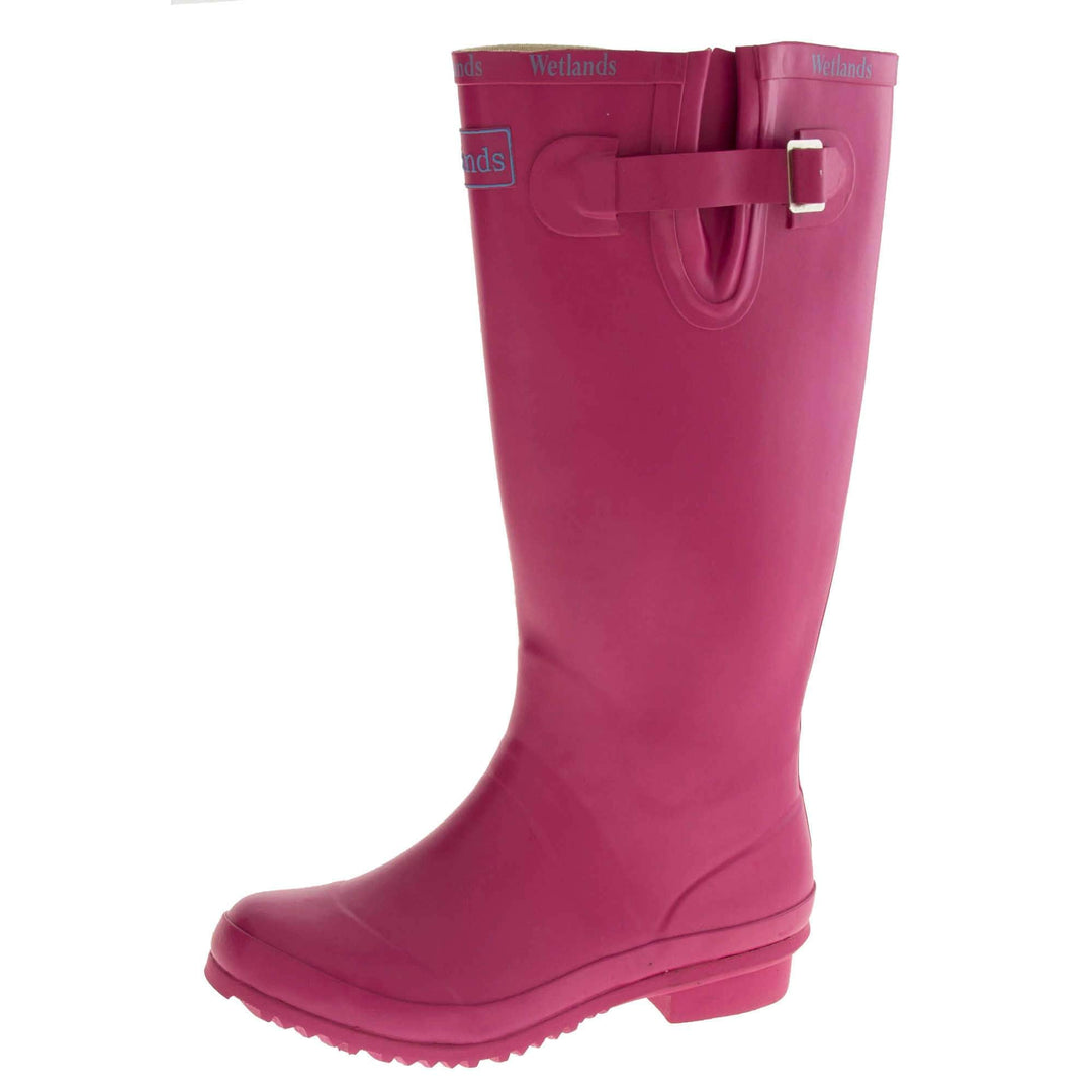 Pink wellington boots. Bright pink rubber waterproof wellington boots. Just below knee height. With a small heel and deep tread to the sole. Pink Wetlands Brand to the front of the boot near the top. Wetlands written in Lilac numerous times around the rim of the boot. Side strap with buckle to adjust the calf width. Textile lining to the inside of the boot. Left foot at an angle.