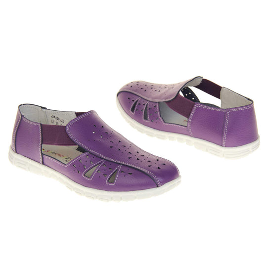 Purple wide fit shoes. Womens classic full foot sandal with a purple leather upper. Strappy sides with cut out designs along the side and centre straps. Purple elasticated straps joining the centre to the backs. White insole and leather lining. White sole with grip to the bottom. Both shoes about an inch apart at a slight angle facing top to tail.