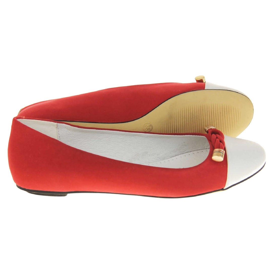 Red ballet flats. Womens ballerina style shoes with a red faux suede upper with white toe. Braided red rope detail to the top with gold studs to the end. White real leather lining and black sole. Both feet from a side profile with the left foot on its side behind the the right foot to show the sole.