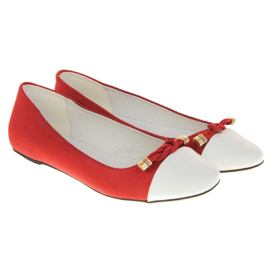 Red ballet flats. Womens ballerina style shoes with a red faux suede upper with white toe. Braided red rope detail to the top with gold studs to the end. White real leather lining and black sole. Both feet together at a slight angle.