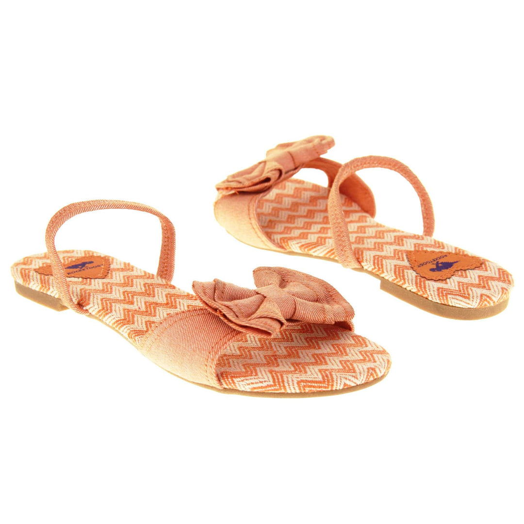 Rocket dog sandals. Classic womens slingback sandals with a orange coral coloured textile straps. orange and cream zig zag print insoles with an orange heart to the bag with Rocket dog logo. Thin beige outsole with a tiny heel. Both feet facing opposite directions.
