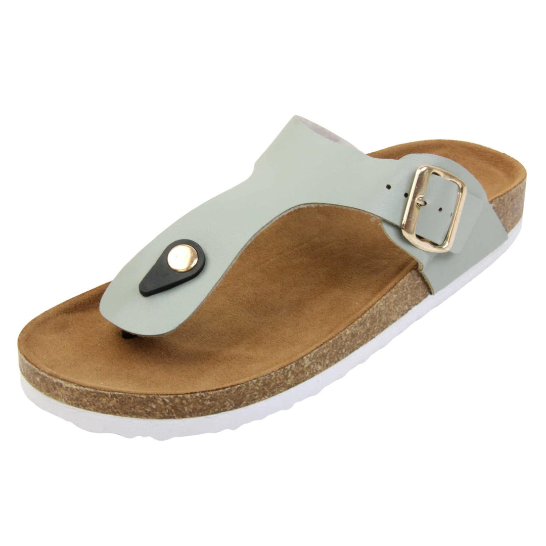Sage flip flops. Sage green faux leather strap with toe post to the front and gold buckle to the outside. Soft tan faux suede footbed with cork effect outsole and white sole. Left foot at an angle.