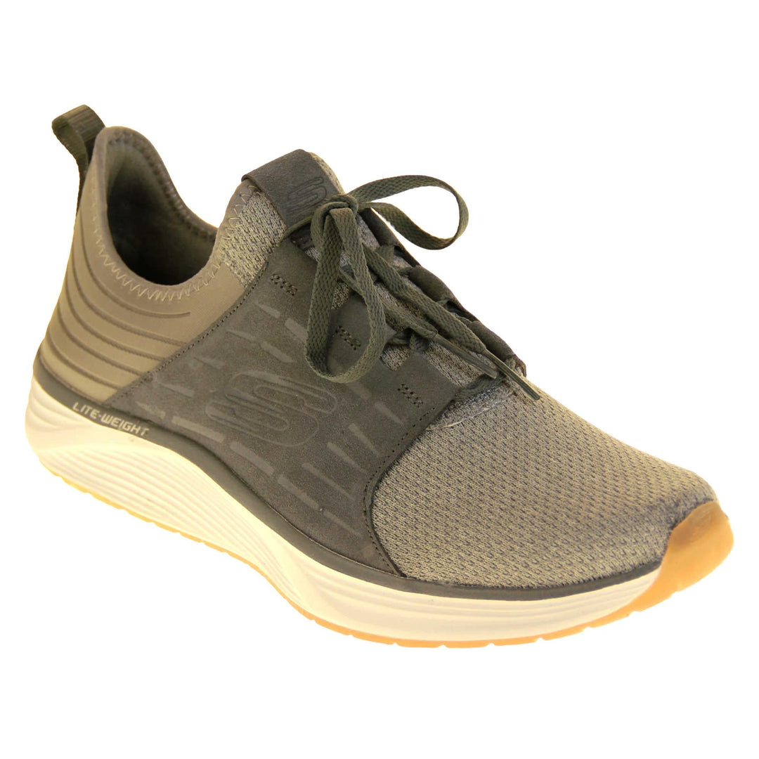 Skechers mens suede trainers. Grey woven mesh fabric upper with dark grey sport suede side overlay panels. With an embossed S skechers logo to the side. Dark grey laces and loop on the heel to help pull on. Chunky white outsole with beige base. Grey textile lining. Right foot at an angle.