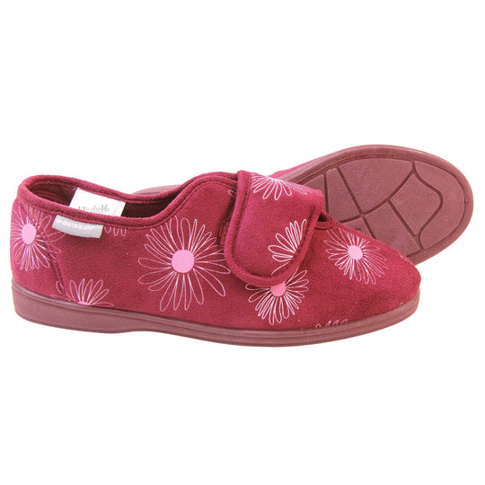 Slippers elderly women. Womens full back slipper. With a plum coloured upper with white daisy design and pink for the middle of the flowers. Touch fasten strap over the top of the foot to adjust the fit. Plum textile lining and firm plum sole. Both feet from a side profile with the left foot on its side behind the the right foot to show the sole.