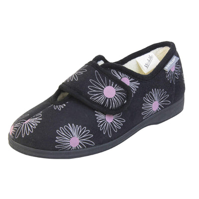 Slippers for elderly with swollen feet. Womens full-back slipper. Black upper with a white daisy design and pink for the middle of the flowers. Touch fasten strap over the top of the foot to adjust the fit. Cream fleece lining and firm black sole. Left foot at an angle.