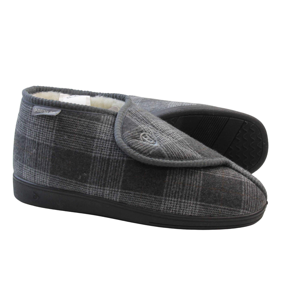 Orthopaedic slippers. Mens orthopaedic slippers in an ankle boot style. With a grey plaid upper and white fleece lining. With an adjustable touch close top with a grey Dunlop logo on. Small grey label to the outer side edge with Dunlop written on. Thick black outdoor sole. Both feet from side profile with the left foot on its side to show the sole.