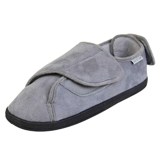 Mens adjustable slippers. Full back slippers with grey upper. Adjustable touch fasten strap to the top of the foot and around the back of the heel. Small white label on the outside rim, with Dunlop branding sewn in black. Grey faux fur lining. Firm black sole. Left foot at an angle.