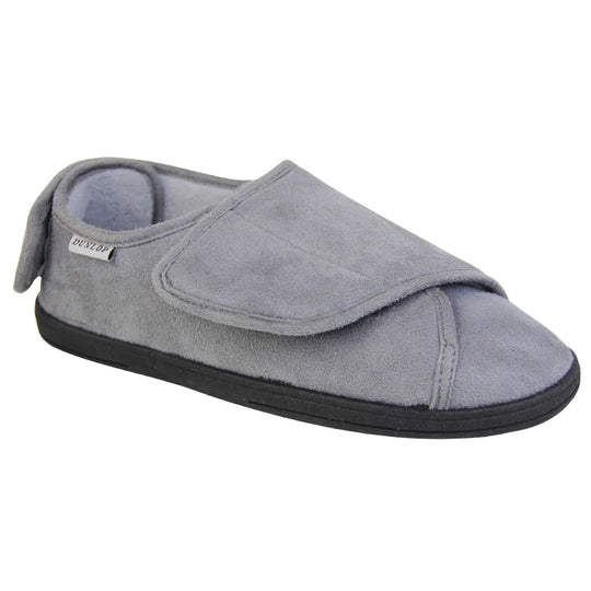 Mens adjustable slippers. Full back slippers with grey upper. Adjustable touch fasten strap to the top of the foot and around the back of the heel. Small white label on the outside rim, with Dunlop branding sewn in black. Grey faux fur lining. Firm black sole. Right foot at an angle.