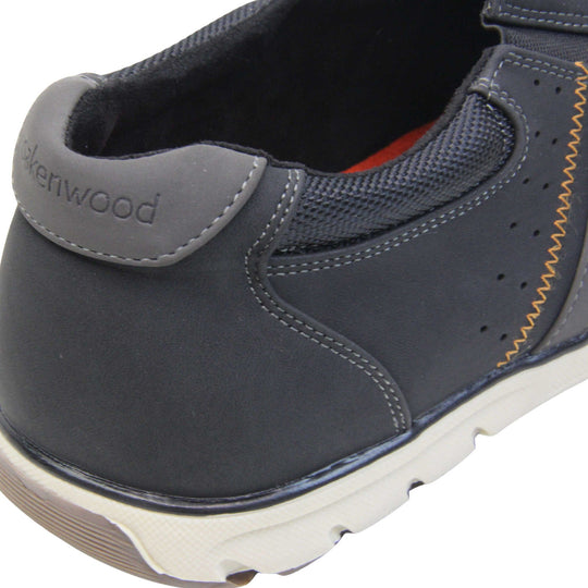 Smart black trainers mens. Slip on trainers with black faux suede uppers. Elasticated side gussets in black and a grey diagonal stripe to the side of the shoe. Black collar around the neck of the shoe with Oakenwood branding to the heel. Black lining and a white outsole with grey sole. Left foot close up of the heel of the shoe to show the lining and heel branding of the shoe.