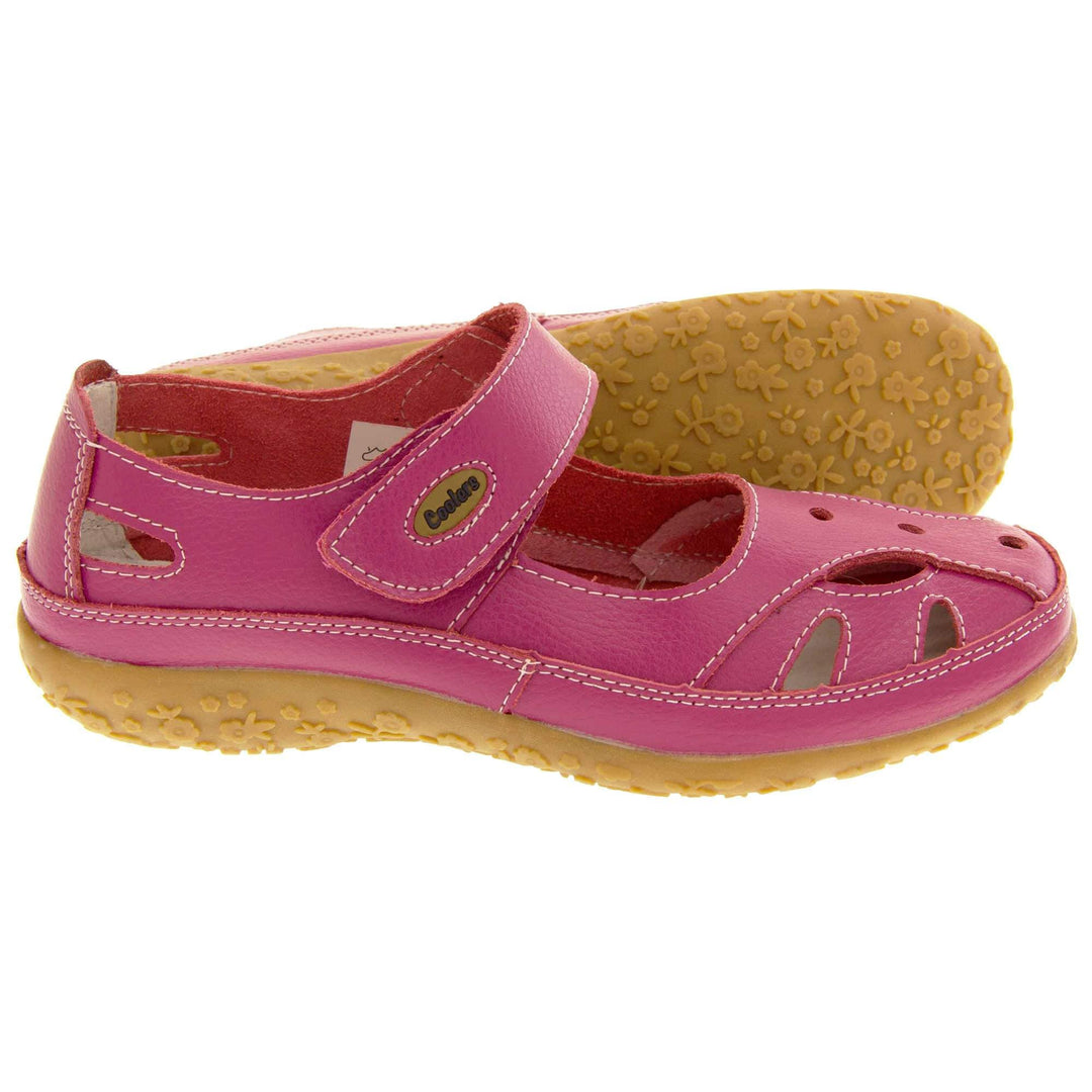 Soft leather shoes. Mary Jane style shoes. Pink leather uppers with white stitching detail. Pink touch fasten strap over the foot with brown oval, where it fastens, with Coolers logo in the centre. Cut outs in the middle, edges and heel of the shoes. Brown synthetic soles with flower design grips. Both feet from a side profile with left foot on its side behind the right to show the sole.