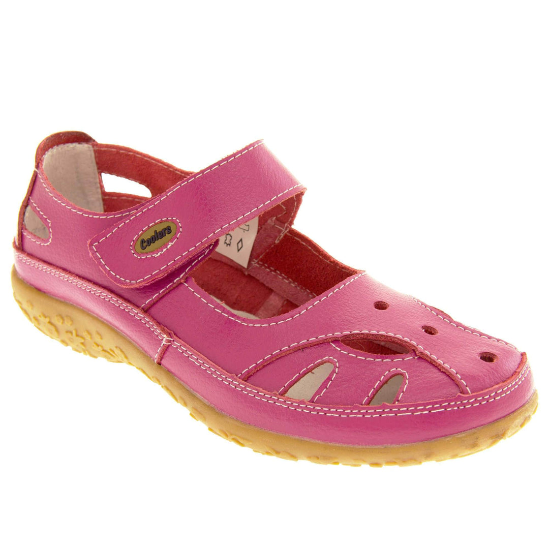 Soft leather shoes. Mary Jane style shoes. Pink leather uppers with white stitching detail. Pink touch fasten strap over the foot with brown oval, where it fastens, with Coolers logo in the centre. Cut outs in the middle, edges and heel of the shoes. Brown synthetic soles with flower design grips. Right foot at an angle.