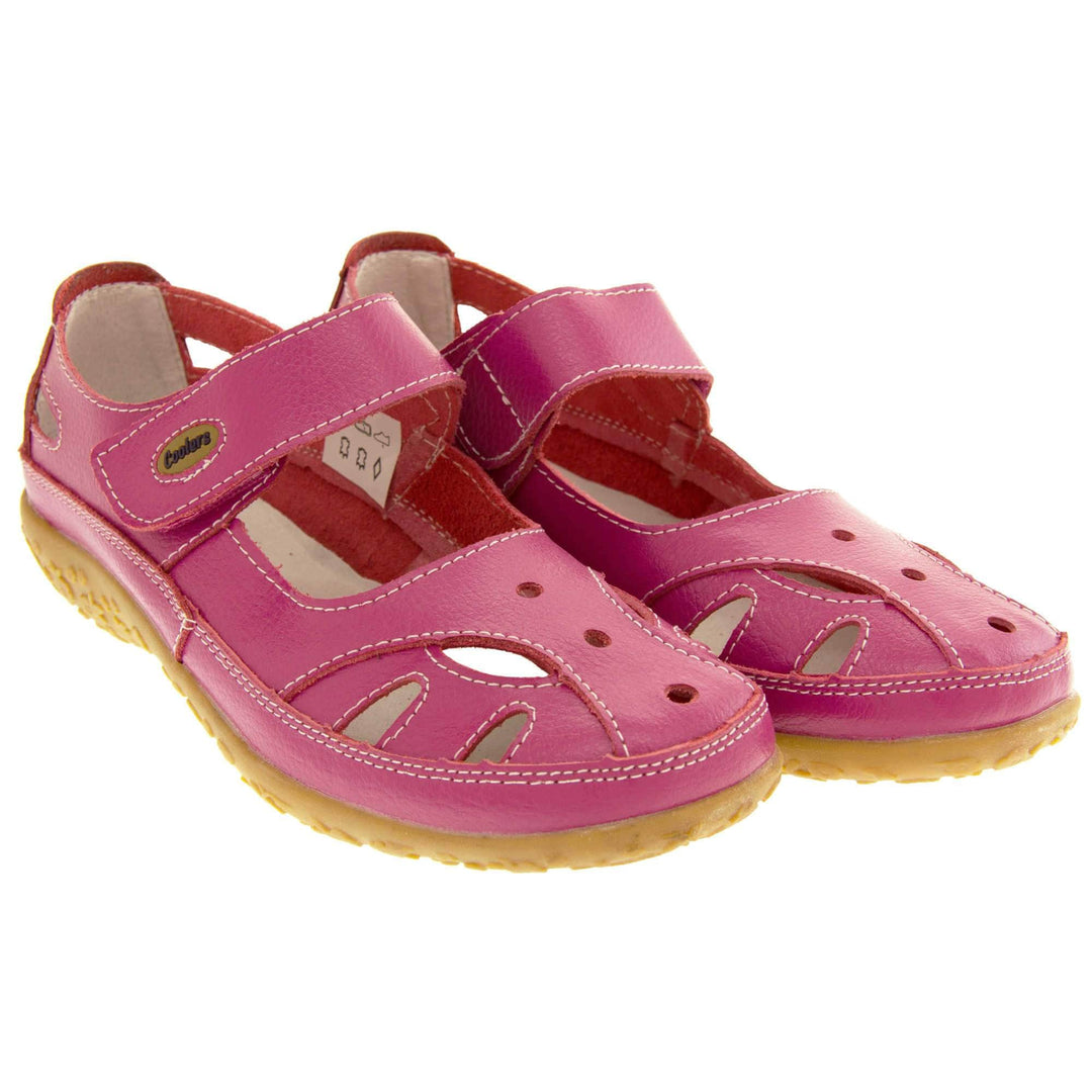 Soft leather shoes. Mary Jane style shoes. Pink leather uppers with white stitching detail. Pink touch fasten strap over the foot with brown oval, where it fastens, with Coolers logo in the centre. Cut outs in the middle, edges and heel of the shoes. Brown synthetic soles with flower design grips. Both shoes together from an angle
