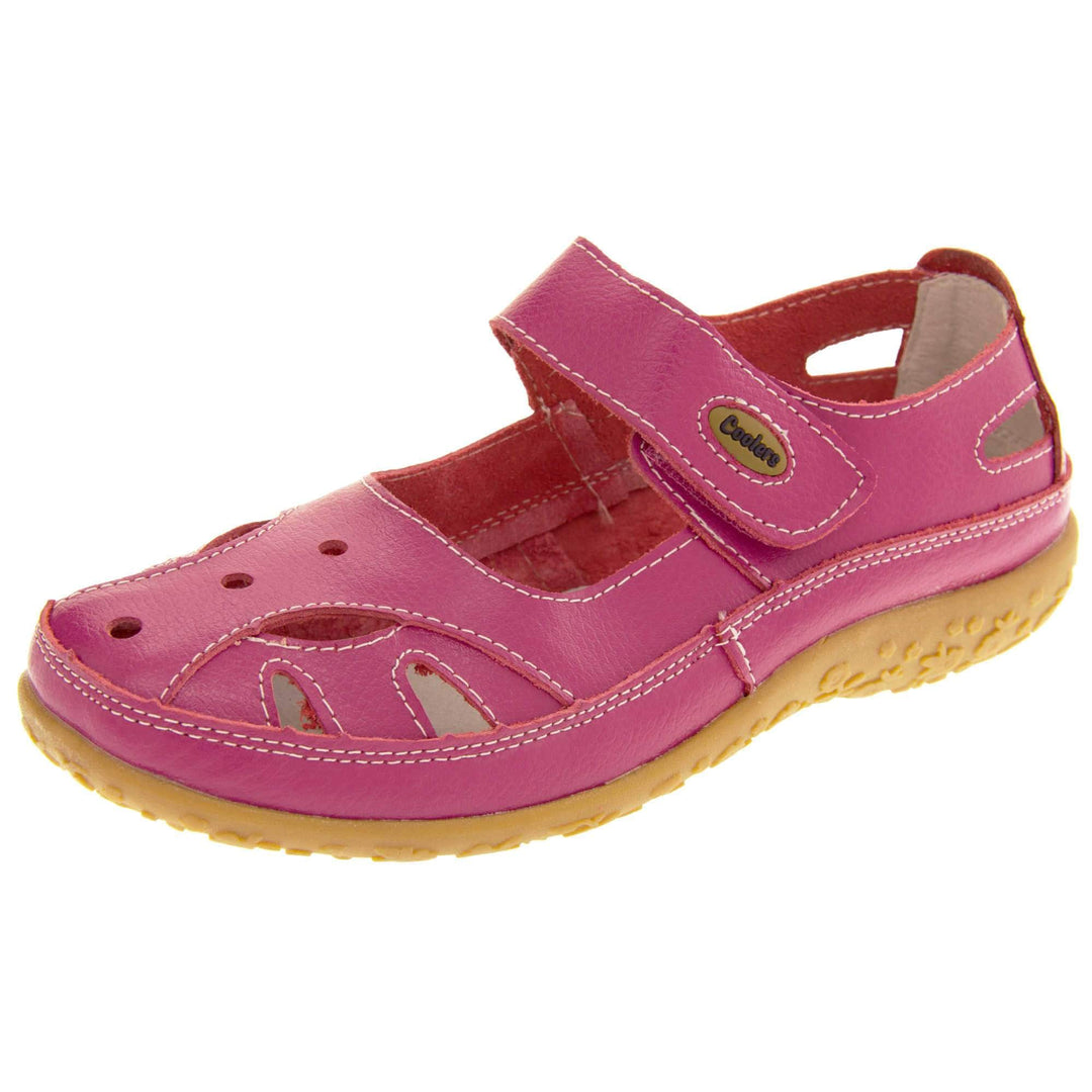 Soft leather shoes. Mary Jane style shoes. Pink leather uppers with white stitching detail. Pink touch fasten strap over the foot with brown oval, where it fastens, with Coolers logo in the centre. Cut outs in the middle, edges and heel of the shoes. Brown synthetic soles with flower design grips. Left foot at an angle.