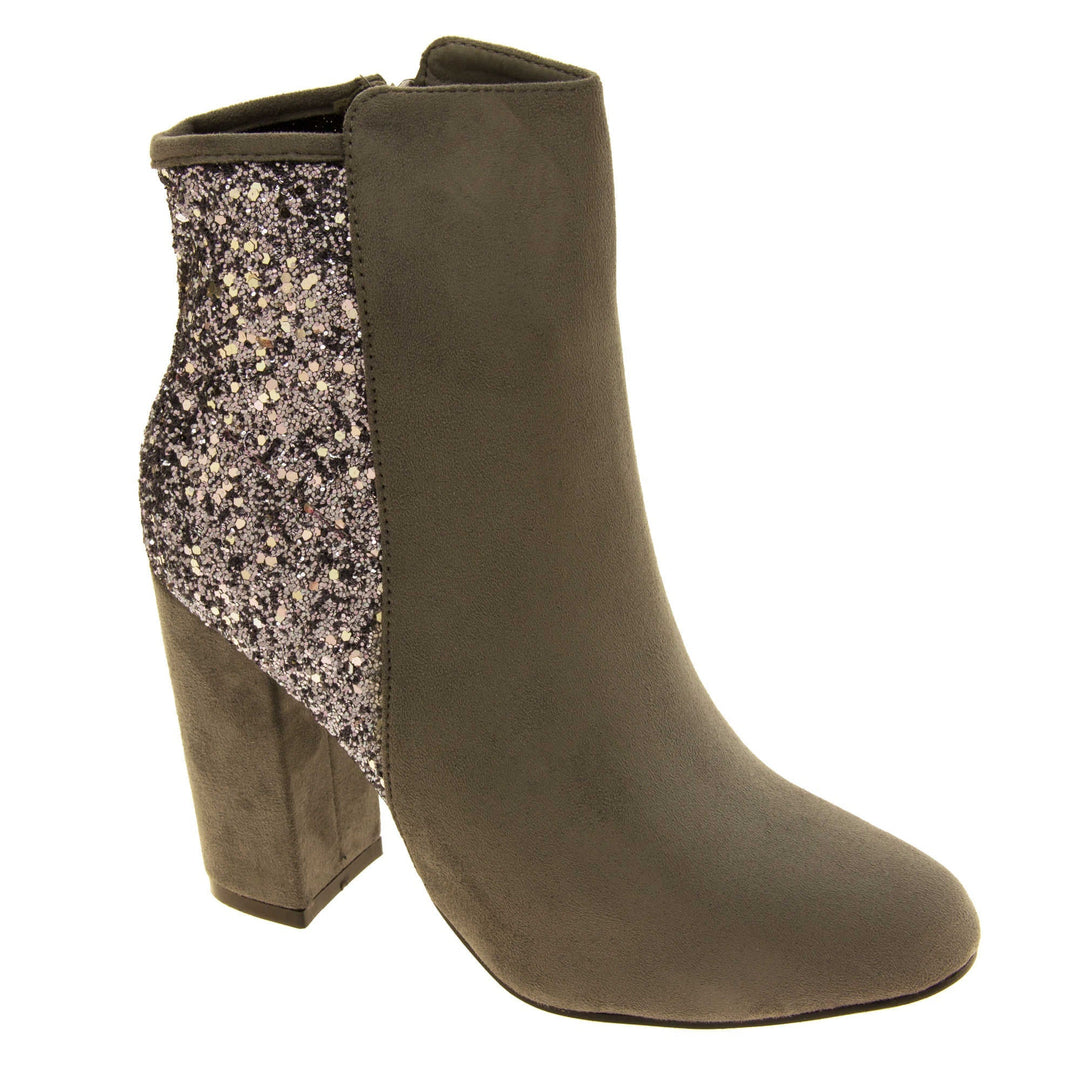 Suede ankle boots women. Grey faux suede upper with the back half of the boot covered in silver glitter. Zip fastening down the inside leg of the boot. With a grey block high heel and black sole. Right foot at an angle.