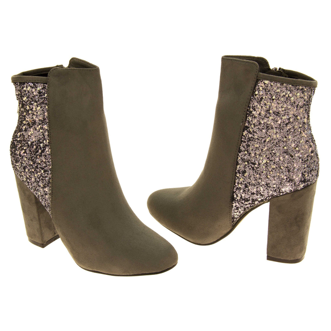 Suede ankle boots women. Grey faux suede upper with the back half of the boot covered in silver glitter. Zip fastening down the inside leg of the boot. With a grey block high heel and black sole. Both feet from a slight angle facing top to tail.