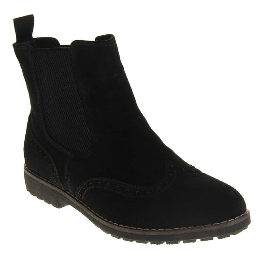 Suede brogue boots women's. Ankle boot style with brogue detailing. With a black suede upper. Black elasticated panels at the ankles and a black loop at the heel to help pull them on. Black coloured sole with a very slight heel. Right foot at an angle.
