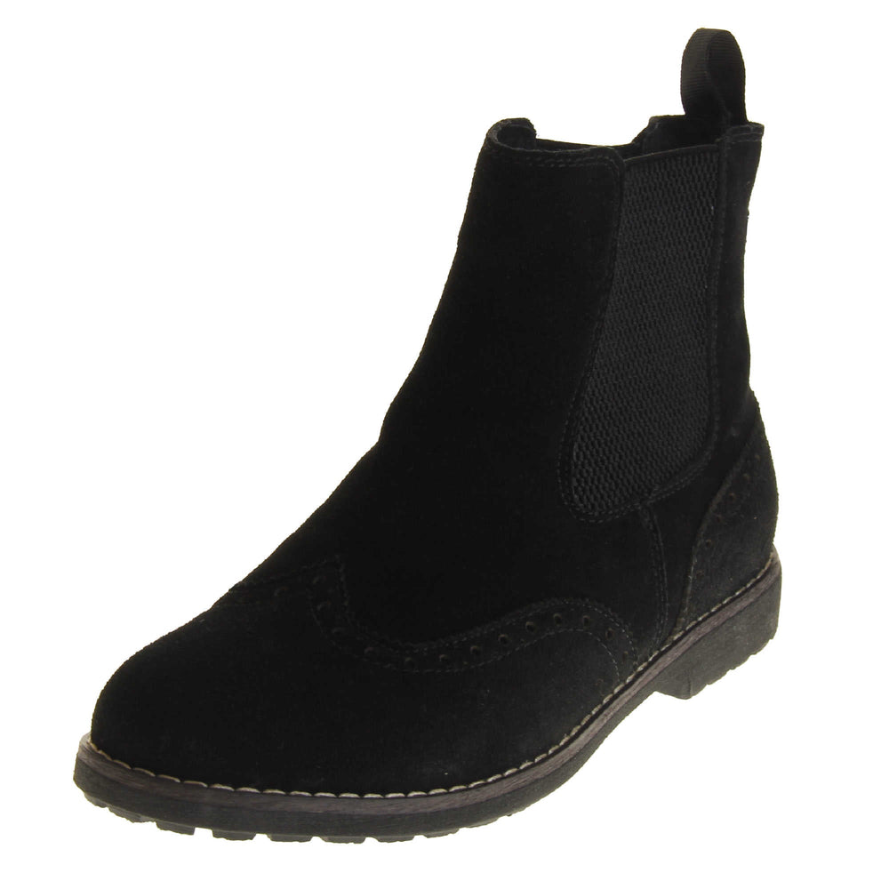  Suede brogue boots women's. Ankle boot style with brogue detailing. With a black suede upper. Black elasticated panels at the ankles and a black loop at the heel to help pull them on. Black coloured sole with a very slight heel. Left foot at an angle.