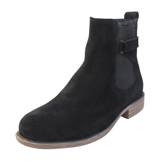 Suede leather ankle boots. Chelsea boot style with a black suede upper. Black elasticated panels at the ankles with straps in a zigzag across the panel. Black loop at the back to help pull them on. Brown sole with a slight heel. Left foot at an angle.