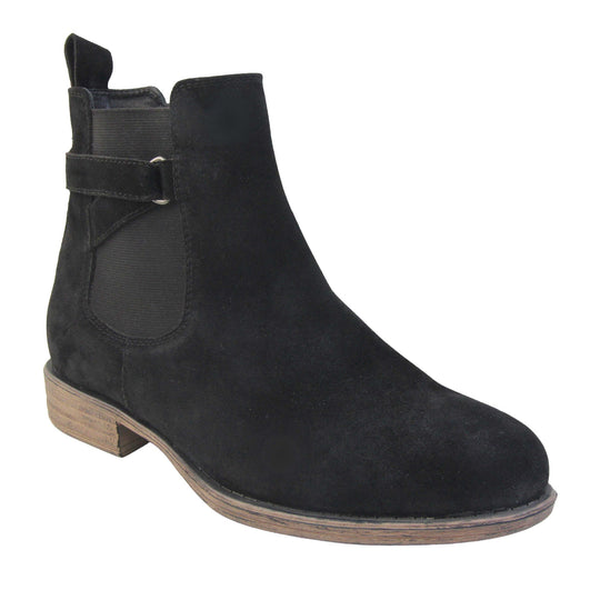 Suede leather ankle boots. Chelsea boot style with a black suede upper. Black elasticated panels at the ankles with straps in a zigzag across the panel. Black loop at the back to help pull them on. Brown sole with a slight heel. Right foot at an angle.