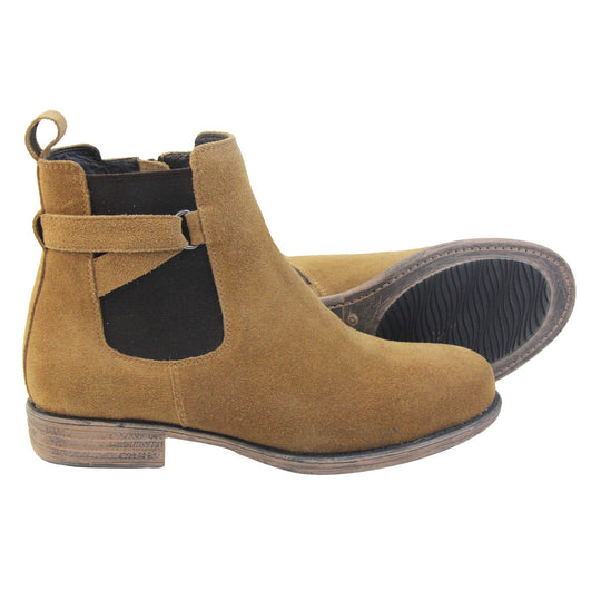 Suede leather Chelsea boots. Women's ankle boot with a tan suede upper. Black elasticated panels at the ankles with straps in a zigzag across the panel. Brown loop at the back to help pull them on. Brown sole with a slight heel. Both feet from a side profile with the left foot on its side to show the sole.
